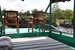 Orangutan Kelotok Houseboat for 6 person في بانكالان بون: كرسيين وسرير على ظهر قارب