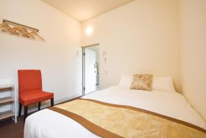 una camera da letto con un letto e una sedia rossa di Comfy Stay Sarusawaike a Nara
