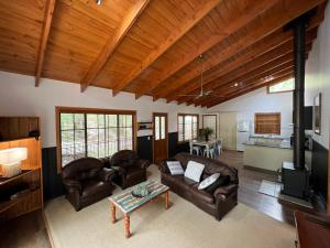 uma sala de estar com sofás de couro e uma cozinha em The Blue Wren Lodge 111 em Halls Gap