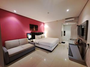 een slaapkamer met een bed, een bank en een tv bij Arrayan Malioboro Syariah in Yogyakarta