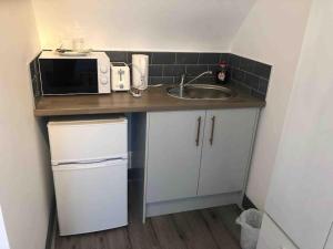 a small kitchen with a sink and a microwave at Newly refurbished studio, great location 8 studios in Nottingham
