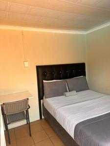 a bedroom with a bed and a table and a chair at L-PACK PRIMROSe in Germiston +29 photos