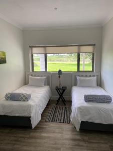 two beds in a room with a window at TAMO Guest Farm in Plettenberg Bay