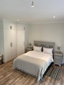 una camera da letto con un grande letto bianco con due comodini di TAMO Guest Farm a Plettenberg Bay