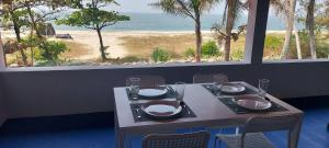 a table with plates and napkins and a view of the beach at Happy Seas Beach Villa in Alleppey