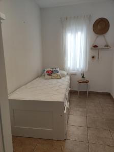 a white bed in a room with a window at Apartament Ampolla Port in L'Ampolla