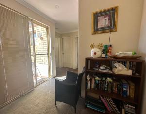 ein Wohnzimmer mit einem Bücherregal und einem Stuhl in der Unterkunft Joondalup Guest House in Perth