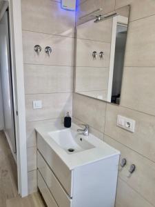 a bathroom with a white sink and a mirror at Apartamentos RG Hospital Valme in Seville