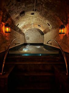 パレルモにあるPALAZZO SANTAMARINA Luxury Suite & Spaの石造りのトンネル内のバスタブ(照明付)