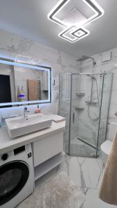 ein Badezimmer mit einer Dusche, einem Waschbecken und einer Waschmaschine in der Unterkunft Modern Gagarina Avenue in Dnipro