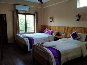 a hotel room with two beds and a window at HOTEL CROWN HORIZON in Sauraha