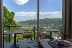 un balcón con mesas y sillas y una gran ventana en Rivora Heights en Kandy