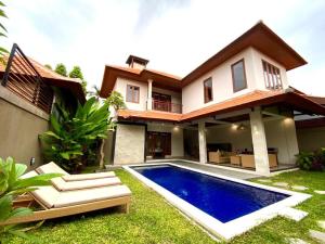 a house with a swimming pool in front of it at Three Brothers Bungalows & Villas in Legian