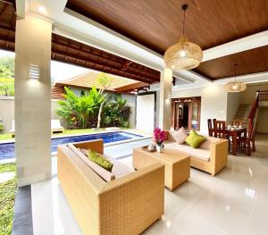 an outdoor living room with couches and a swimming pool at Three Brothers Bungalows & Villas in Legian