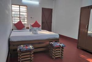 a bedroom with a bed with red pillows and an elephant on it at STAYMAKER Gharana Resort in Bolpur
