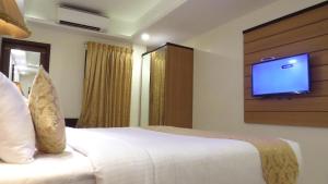 Schlafzimmer mit einem Bett und einem TV an der Wand in der Unterkunft Hotel Rajadhani in Thiruvananthapuram