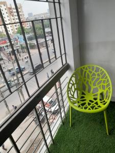 einem grünen Stuhl vor einem Fenster in der Unterkunft Hotel Shahin residential in Dhaka