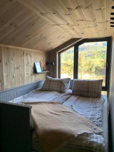 Cama en habitación pequeña con ventana grande en Gaustablikk Sportshytte midt i naturen, en Rjukan