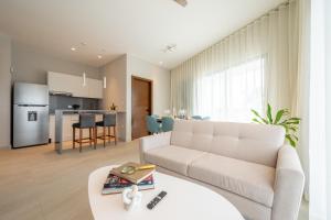 a living room with a couch and a table at Kippal - Modern Oasis - ApartHotel in Cozumel