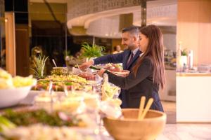 a man and woman serving food at a buffet at Century Marina Hotel - Lusail in Lusail
