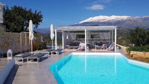 a house with a swimming pool with a mountain in the background at Galini Breeze in Agia Galini