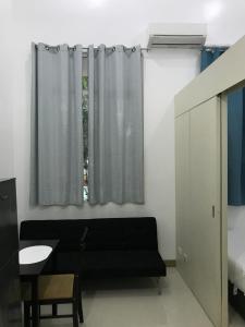 a living room with a black couch and a window at South Residences staycation in Manila +6 photos