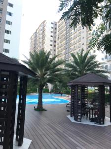 a deck with chairs and a gazebo and palm trees at South Residences staycation in Manila