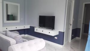 - un salon avec une télévision et un canapé blanc dans l'établissement Aranya pool villa, à Ban Phu Yai
