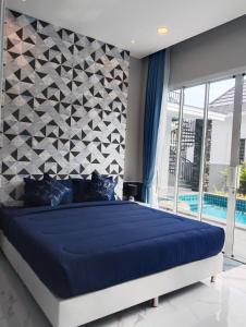 une chambre avec un grand lit bleu et un mur géométrique dans l'établissement Aranya pool villa, à Ban Phu Yai 28 autres photos