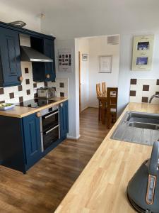 a kitchen with blue cabinets and a counter top at Cumberland Avenue prenton Wirral 3bed detached house with a lovely view looking out on to a field from the rear close to all amenities in Birkenhead