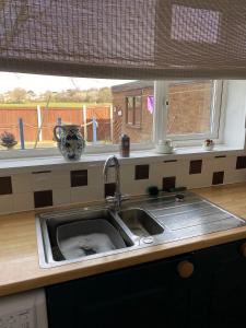 um lavatório de cozinha em frente a uma janela com uma janela em Cumberland Avenue prenton Wirral 3bed detached house with a lovely view looking out on to a field from the rear close to all amenities em Birkenhead