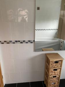 a bathroom with white tiled walls and a mirror at Cumberland Avenue prenton Wirral 3bed detached house with a lovely view looking out on to a field from the rear close to all amenities in Birkenhead