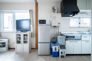 Il comprend une cuisine équipée d'appareils électroménagers blancs et une télévision. dans l'établissement Sumiyoshi House Room A, à Otaru