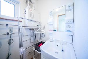 a white bathroom with a sink and a mirror at Sumiyoshi House Room B in Otaru