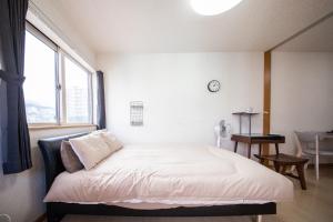 a bed in a room with a large window at Sumiyoshi House Room B in Otaru