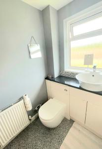 a bathroom with a white toilet and a sink at 5min Drive to Luton Airport, 2 Train Stations & Motorway - FREE PARKING - LATE CHECK OUT 11AM - Quiet & Peaceful Location with a relaxing Garden - ONLY 25min drive to North LONDON - FREE WIFI in Luton