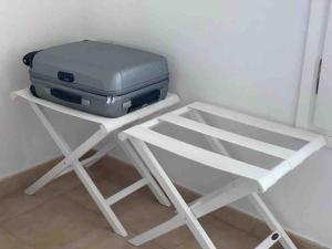 Un taburete blanco con una maleta encima. en Calan Blanes con piscina, en Ciutadella