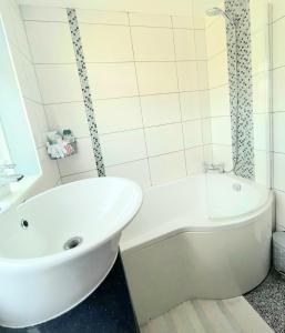 a white bathroom with a tub and a sink at 5min Drive to Luton Airport, 2 Train Stations & Motorway - FREE PARKING - LATE CHECK OUT 11AM - Quiet & Peaceful Location with a relaxing Garden - ONLY 25min drive to North LONDON - FREE WIFI in Luton