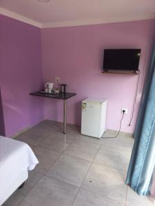 a room with a purple wall with a small refrigerator and a table at Queenz Bed & Breakfast in Durban
