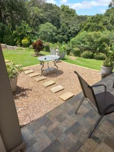 a patio with a table and a chair in a yard at Queenz Bed & Breakfast in Durban