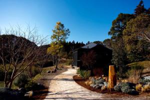 a path leading to a black building on a hill at HARUKA KANATA 森のヴィラ in Minamiboso