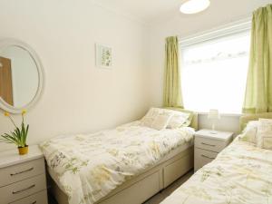 two beds in a bedroom with a mirror and a window at 21 Siesta Mar in Mundesley