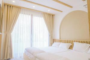 a bedroom with two beds and a large window at BaPhu Apartment - 5BR - 5 mins walk to My Khe beach in Da Nang