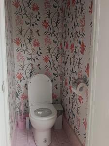 a bathroom with a toilet with floral wallpaper at Green Acres Village in Moalboal