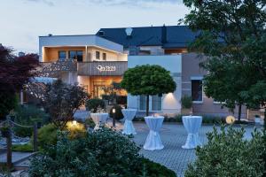 a garden with white chairs in front of a building at Restaurant & Hotel Dabuki in Neutal