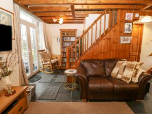 a living room with a leather couch and a staircase at Bwthyn Ael Y Bryn in Dolbenmaen