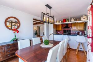 eine Küche und ein Esszimmer mit einem Holztisch und weißen Stühlen in der Unterkunft Casa Honiol, private and spacious villa with sea views in Cala en Porter