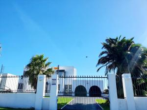 a white fence with palm trees in front of a building at La Grace Executive Guesthouse in Amsterdamhoek