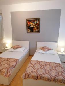two beds in a room with a picture on the wall at Pensiunea Ca La Mama Acasa in Reşiţa