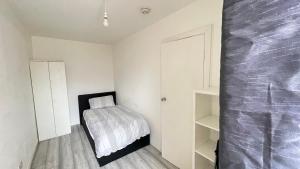 1 dormitorio pequeño con 1 cama y paredes blancas en Aaby House in London en Croydon